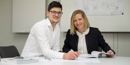 Personen besprechen technische Zeichnungen Zwei Mitarbeiter besprechen technische Zeichnung im Büro