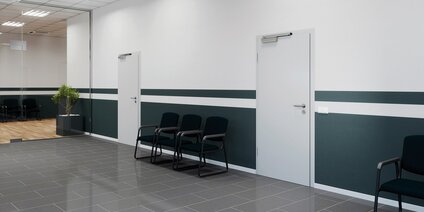 Moderner Büroflur mit Stühlen und Tür Moderner Büroflur mit Wartebereich und weißen Türen