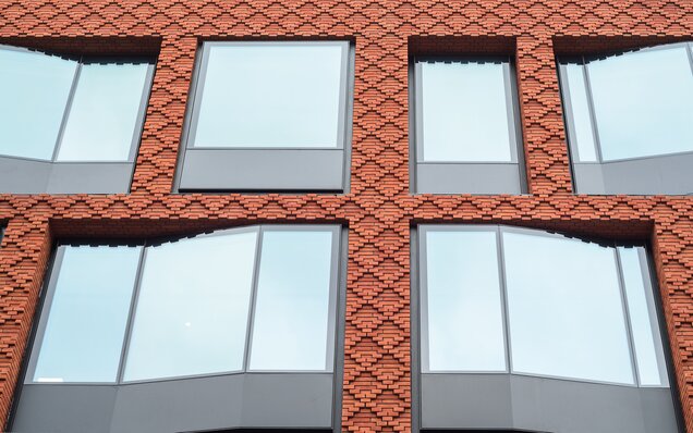 Moderne Fassade mit Ziegeln und großen Fenstern Fassade mit roten Ziegeln und Fenstern