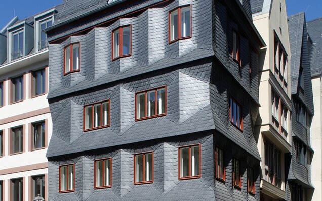 Gebäude mit Schieferfassade und Holzfenstern Fassade mit Schieferplatten und Holzfenstern