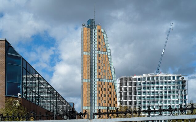 Modernes Hochhaus mit Glas- und Holzfassade Modernes Bürogebäude mit Baukran und Fassaden