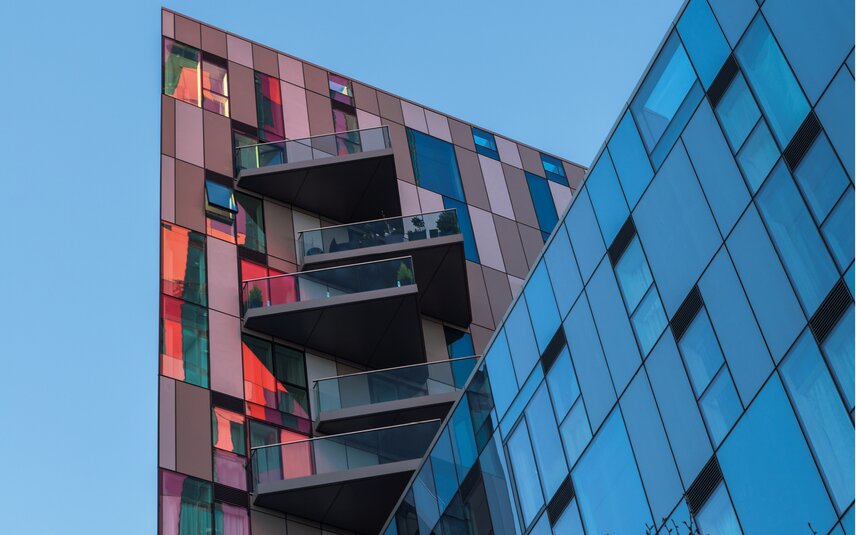 Modernes Wohngebäude mit Glasbalkonen und bunter Fassade Modernes Gebäude mit Glasbalkonen und Fenstern