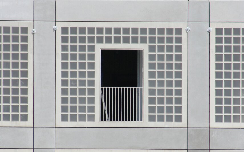 Moderne Betonfassade mit Balkon und Fenstern Graue Fassadenfront mit Balkon und Raster