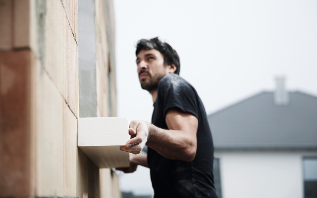 Bauarbeiter montiert GU-Vorbauzarge Bauarbeiter montiert GU-Vorbauzarge an eine Hauswand beim Rohbau